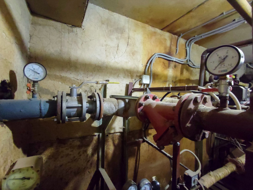 Узел стального трубопровода с манометрами и фланцевыми соединениями в подвале