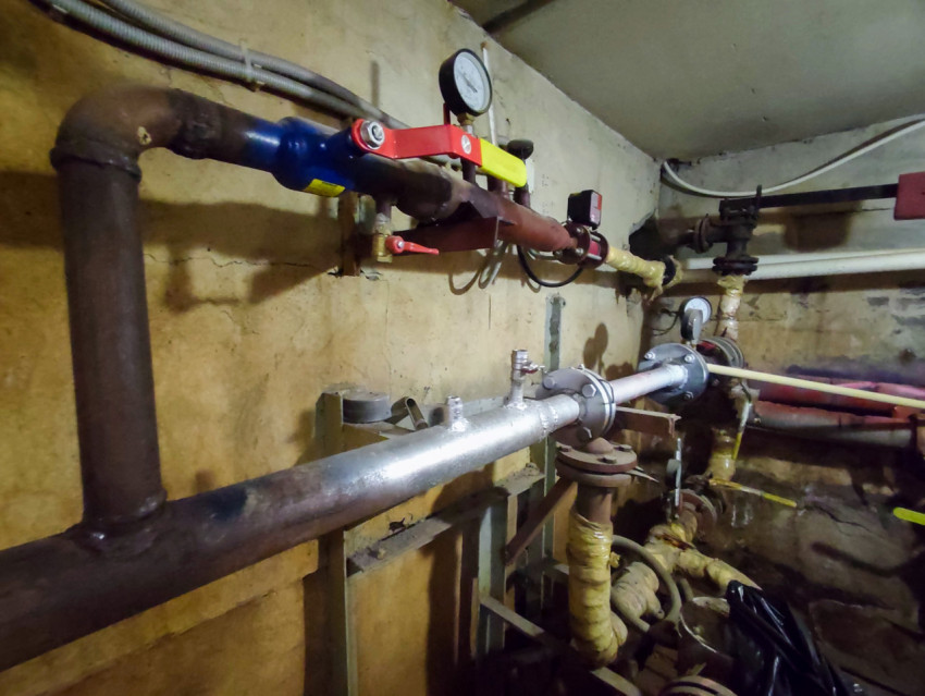 Трубопровод вдоль стены с шаровым краном и манометром в техническом помещении