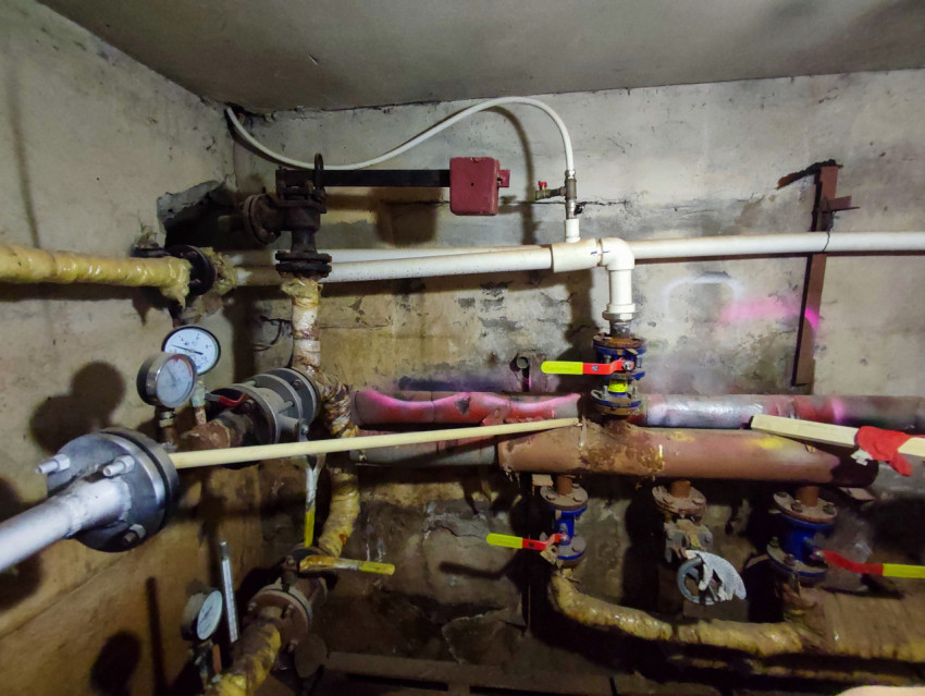 Разводка труб с несколькими кранами и манометрами в подвальном узле коммуникаций