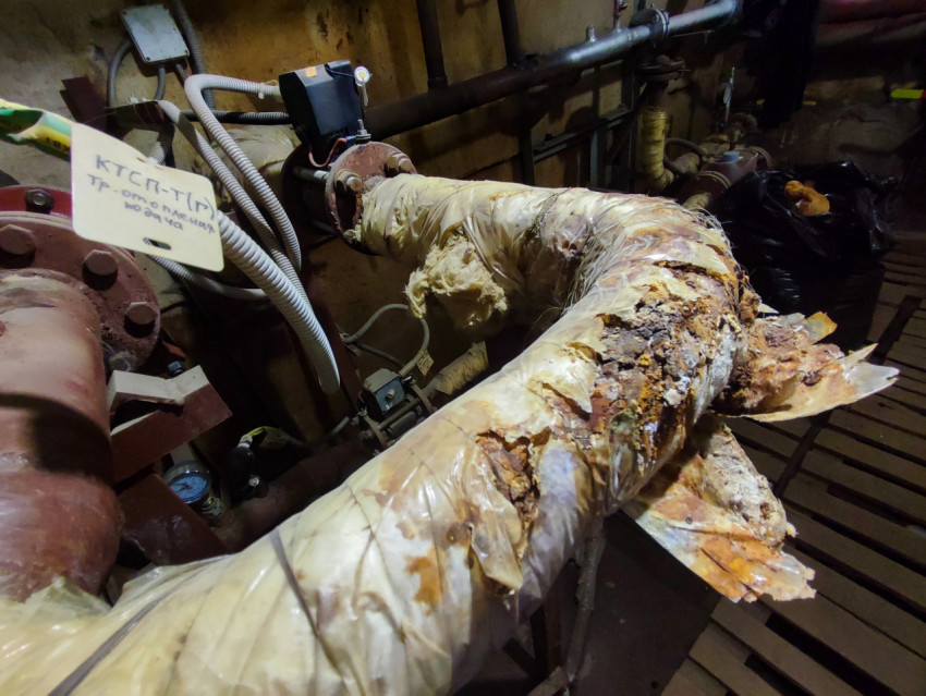 Ржавое колено трубопровода с разрушенной теплоизоляцией на тепловом пункте