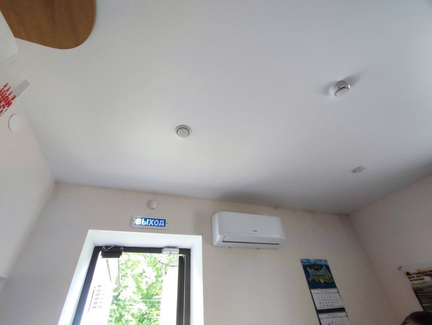 Интерьер помещения с табличкой «ВЫХОД» над окном и настенным кондиционером