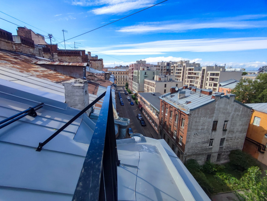 Край крыши с ограждением и панорамой улицы между домами