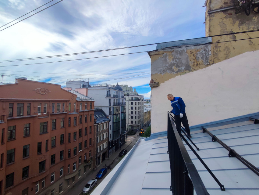 Рабочий на металлической крыше и вид на городскую улицу с высоты