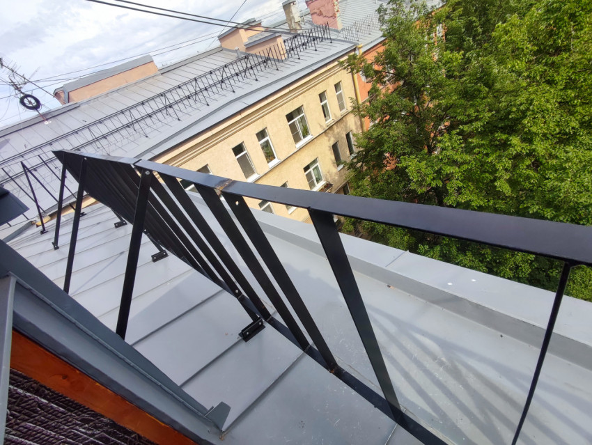Кровельное ограждение на металлической крыше над двором с деревьями и фасадом дома