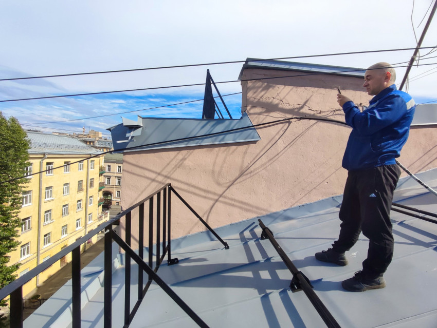 Мужчина со смартфоном на металлической крыше рядом с ограждением