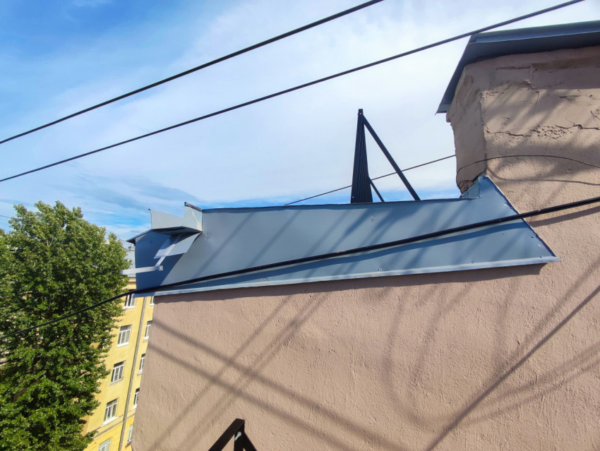 Кровельный отлив на надстройке крыши и воздушные кабели на фоне неба