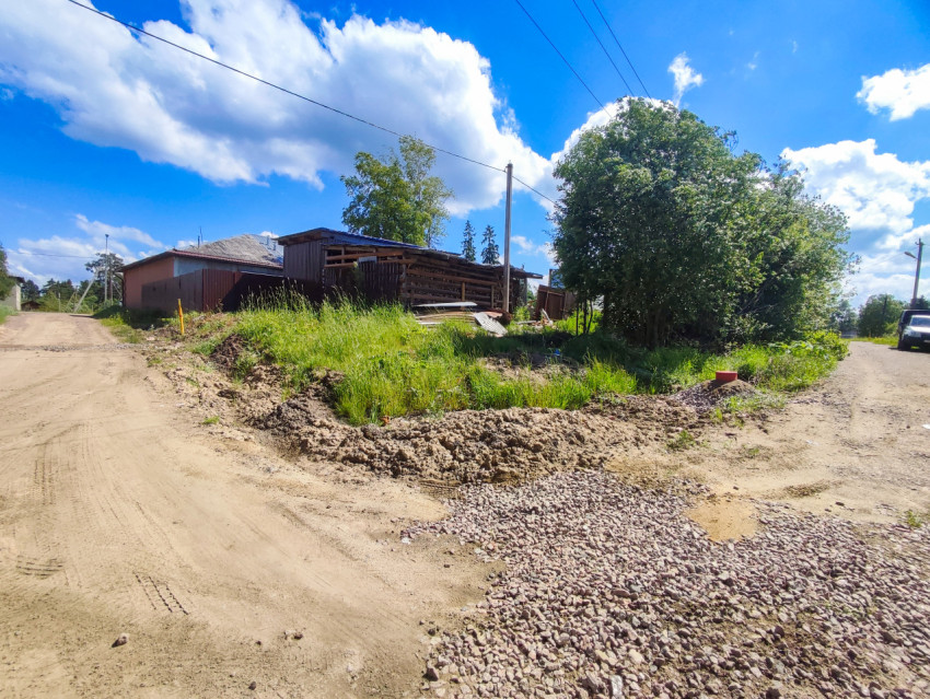 Развилка грунтовых дорог и участок подсыпки щебнем рядом с забором и деревьями