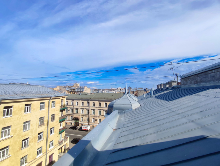 Широкий вид с крыши на квартал многоэтажной застройки с фальцевой кровлей, куполом и проводами