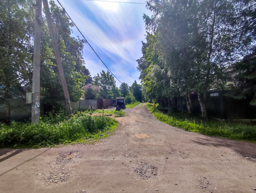 Грунтовая улица с заборами, опорой ЛЭП и адресной табличкой «ул. Полевая, 6»