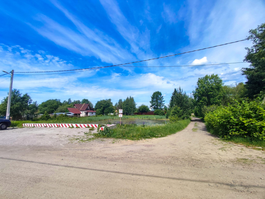 Развилка грунтовых дорог у сельского пруда с ограждением и указателем