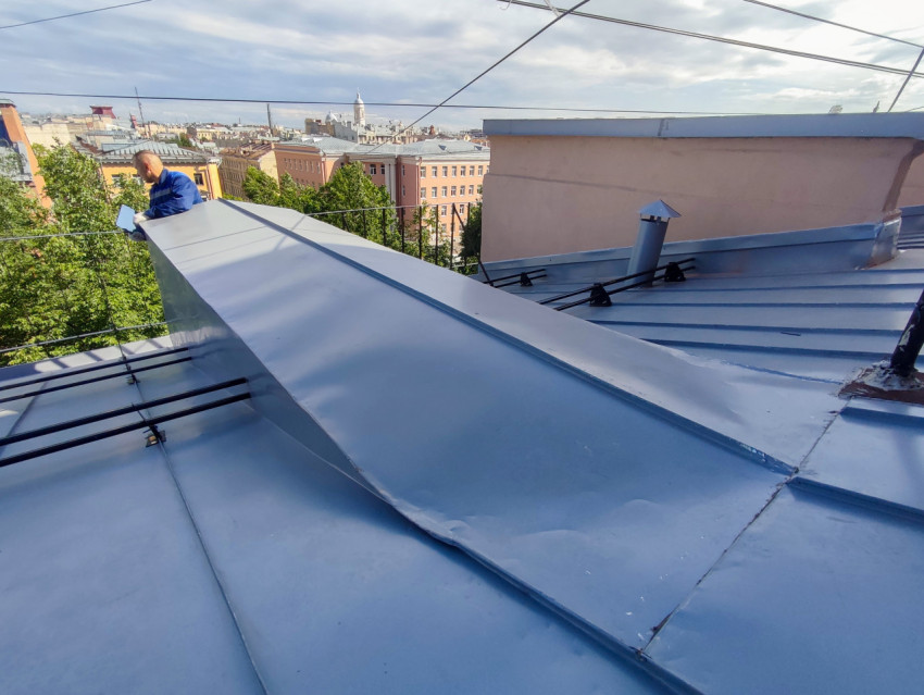 Кровельные работы с большим листом металла на фоне городской панорамы