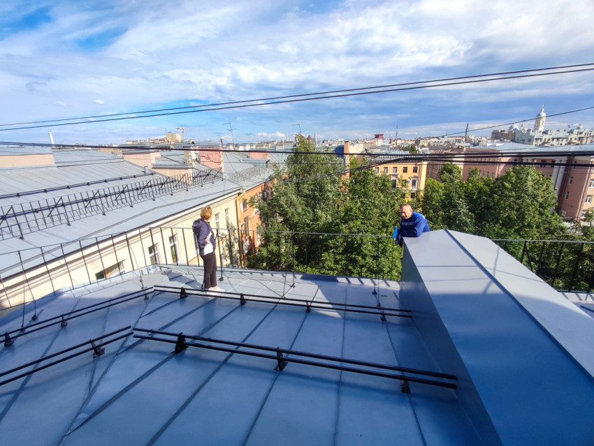 Люди на крыше при осмотре кровли на фоне городской застройки