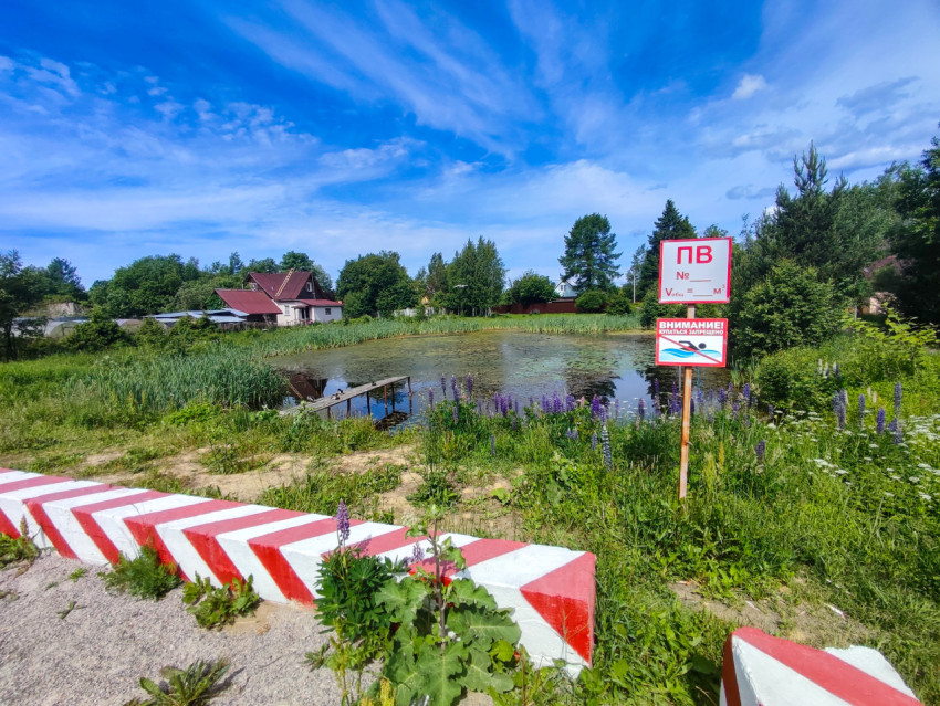 Пожарный водоём у деревенского пруда с предупреждающим щитом