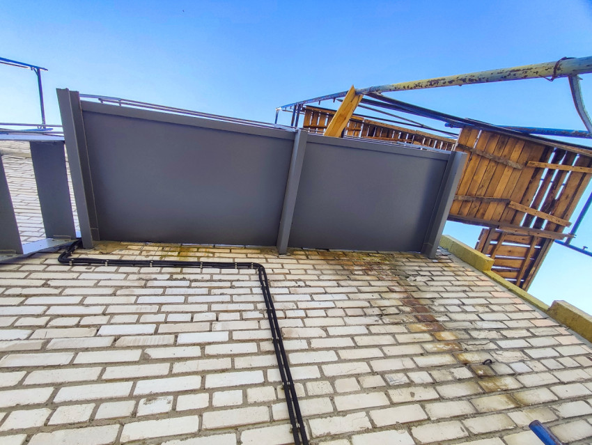 Вид снизу на металлический козырёк или настил и кабельную линию на кирпичном фасаде