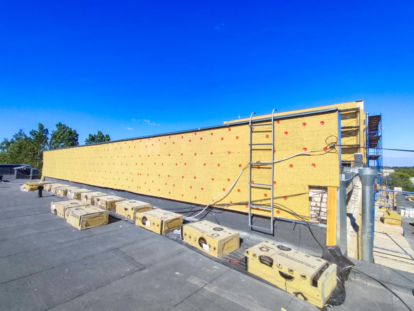 Упаковки теплоизоляции, лестница и фасад из минваты на крыше здания