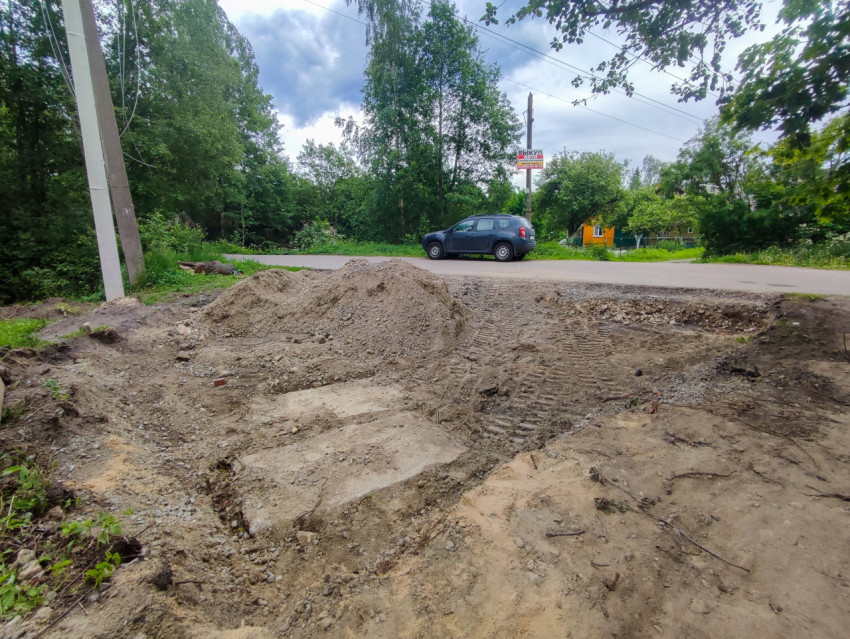 Раскоп и куча грунта на обочине рядом с проезжей частью и автомобилем