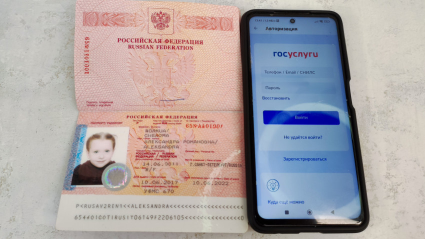 Загранпаспорт РФ с фотографией ребенка и смартфон с Госуслугами