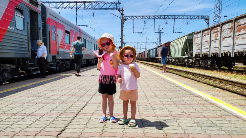 Дети на платформе между пассажирским поездом и грузовыми вагонами