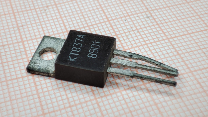 Транзистор КТ837А на фоне миллиметровой бумаги крупным планом