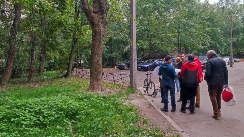 Группа людей с картой обсуждает проект благоустройства возле зелёной зоны