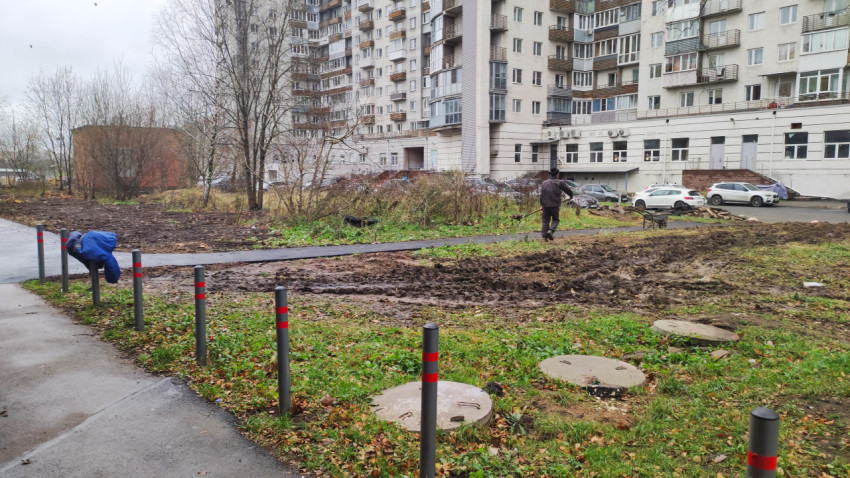 Рабочие проводят благоустройство двора возле многоэтажного дома