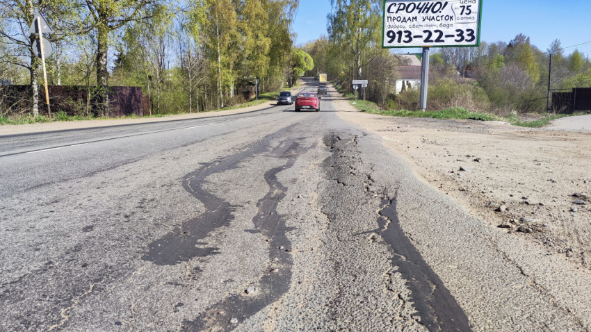 Повреждённое асфальтовое покрытие на загородной трассе с движением автомобилей