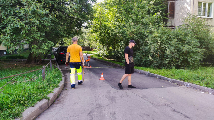 Рабочие проверяют участок асфальтового покрытия во дворе