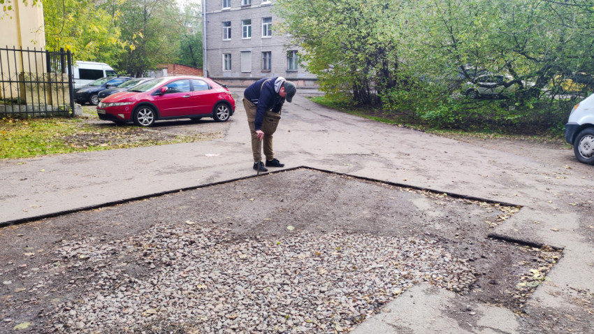 Инженер измеряет высоту кромки асфальта на участке дворовой дороги