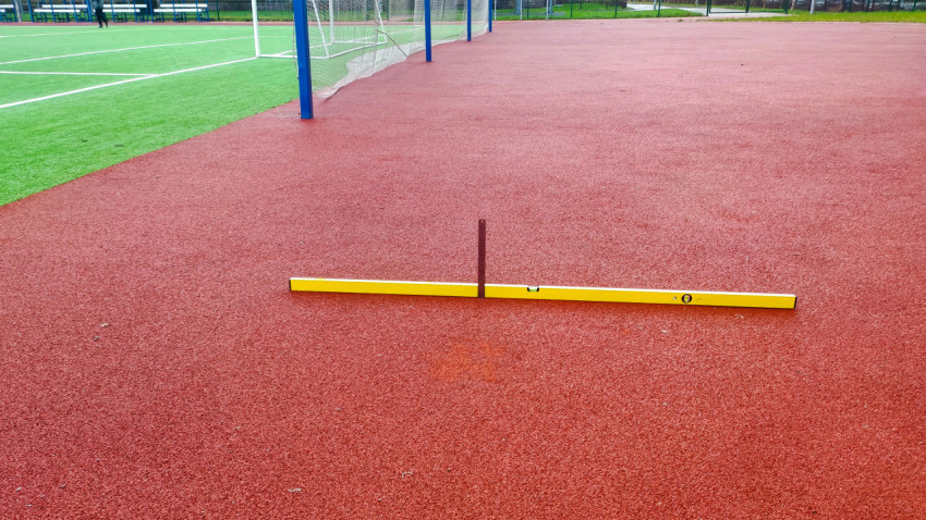 Измерение ровности покрытия у футбольного поля строительным уровнем