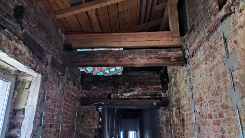Коридор с кирпичными стенами и деревянными перекрытиями на этапе реконструкции