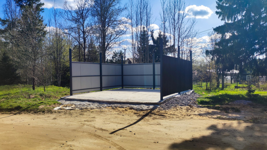 Огороженная площадка на бетонном основании среди деревьев