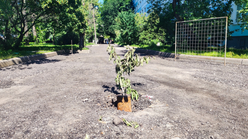 Фрезерованный участок дворовой дороги с щебнем и временным ограждением рядом с жилым домом