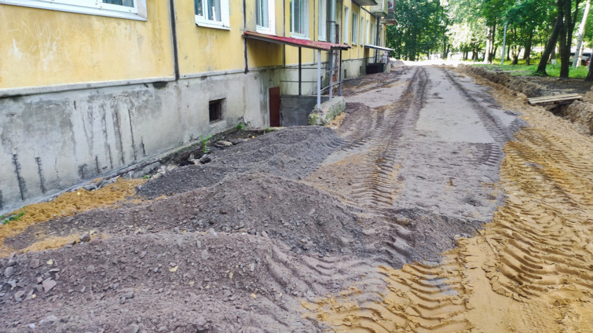 Планировка дворового проезда с кучами щебня и траншеей вдоль фасада жилого дома