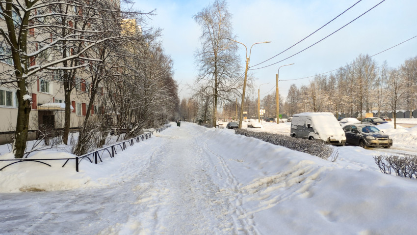 Заснеженная улица с хрущёвкой и припаркованными машинами