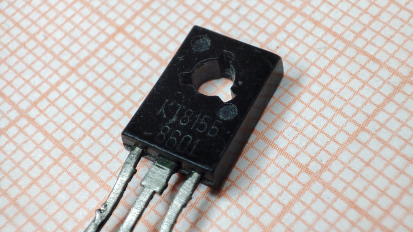 Транзистор КТ815Б типа ТО-126 для сквозного монтажа на фоне миллиметровой бумаги