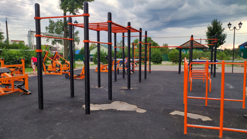 Спортивная площадка в деревне с уличными тренажерами и облачным небом