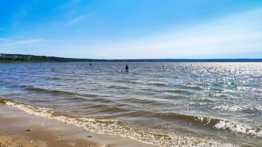 Люди занимаются сапсерфингом на озере в солнечную погоду