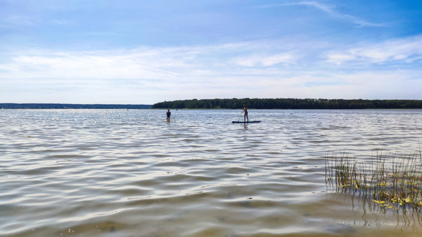 Люди на сапборде и в воде в озере