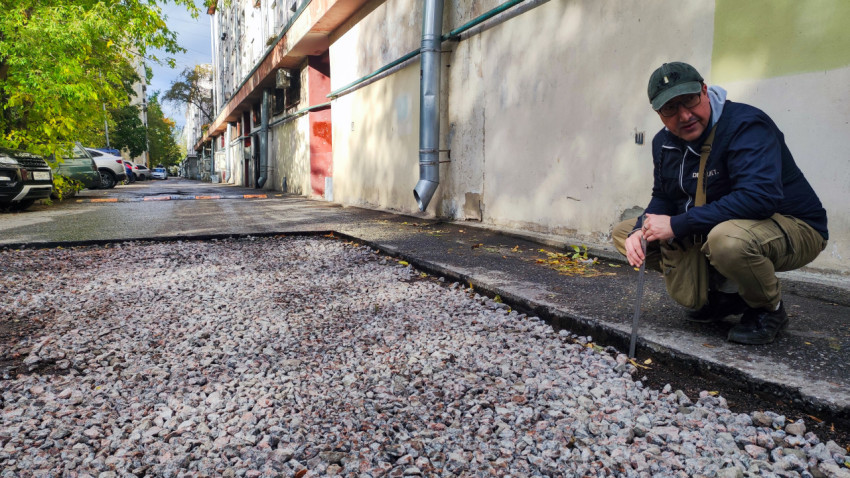 Измерение высоты от щебня до края асфальта вдоль стены жилого дома