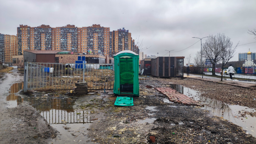 Зелёный биотуалет и жилые дома в пасмурный день