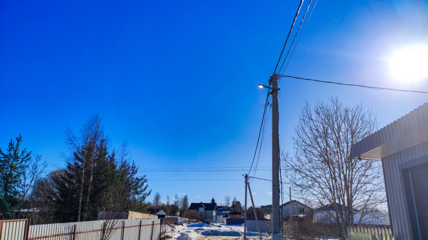 Уличный фонарь на опоре с зимним пейзажем пригородной застройки