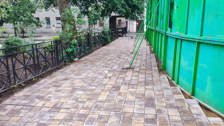 Тротуар из плитки вдоль ограждения спортивной площадки во дворе