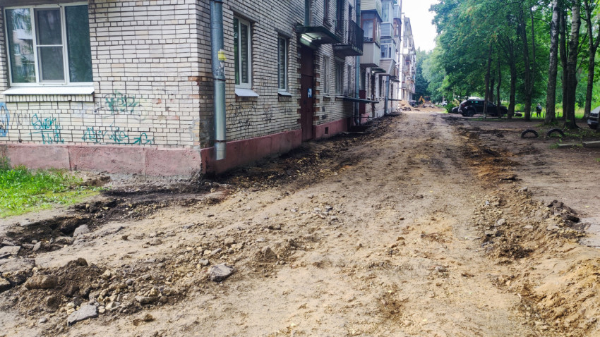 Грунтовая дорога во дворе и строительная техника у жилого дома