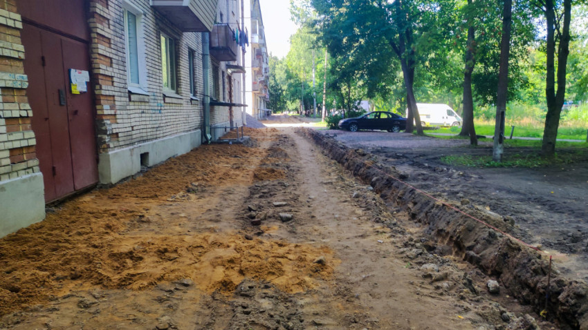 Разметочный шнур и траншея вдоль здания в процессе земляных работ во дворе