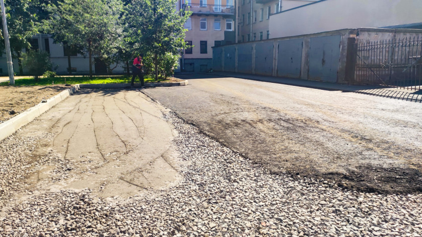 Подготовка основания проезда: слой щебня и песка рядом со старым асфальтом во дворе