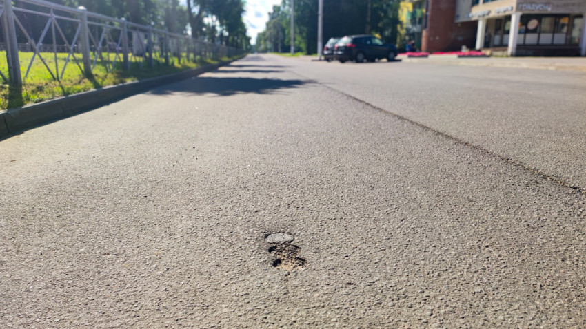 Небольшая выбоина и шов дорожного покрытия крупным планом на асфальте