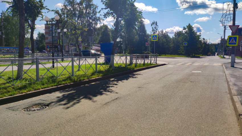 Городской перекрёсток с разметкой «зебра», ограждениями и фонарями вдоль дороги