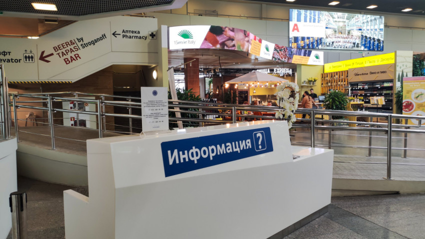 Белая стойка «Информация» на фоне фудкорта и указателя Pharmacy