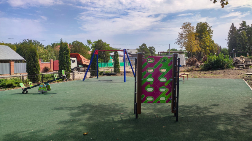 Детская площадка с качелями и балансиром рядом с частным сектором