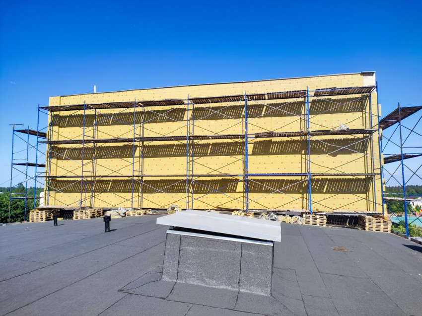 Фасад в минеральной вате и строительные леса на плоской крыше